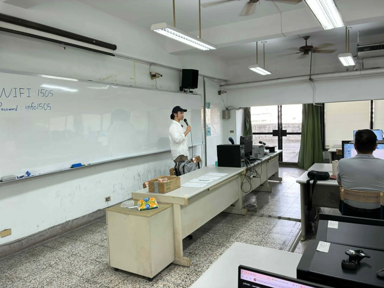 Dawson Wang 站在中正高工電腦教室白板前,用麥克風說明課程開場